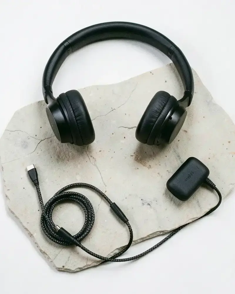 Curated electronics flat lay with headphones, speaker and charger