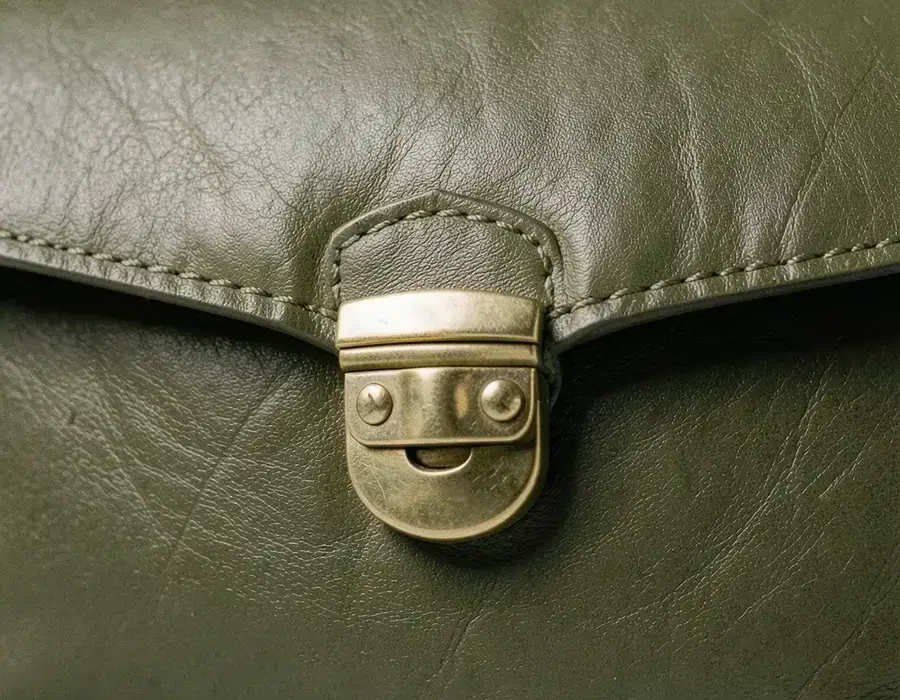 Close detail of a structured leather bag with metal clasp and stitching