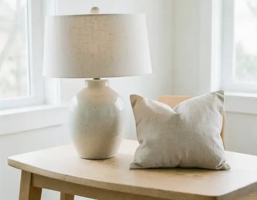 Ceramic table lamp and linen cushion styled on a pale oak table