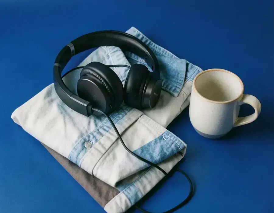 Seasonal bundle of headphones, shirt and ceramic mug on a cobalt backdrop