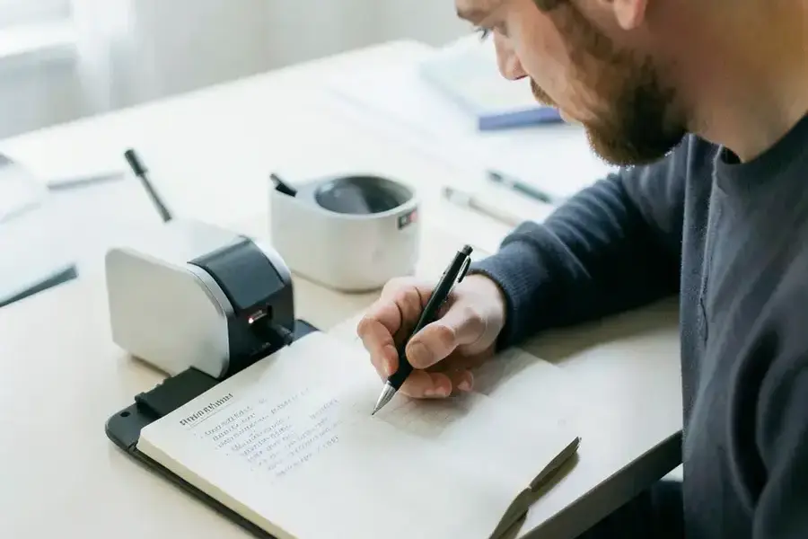 Curator writing product notes next to a sample on a desk