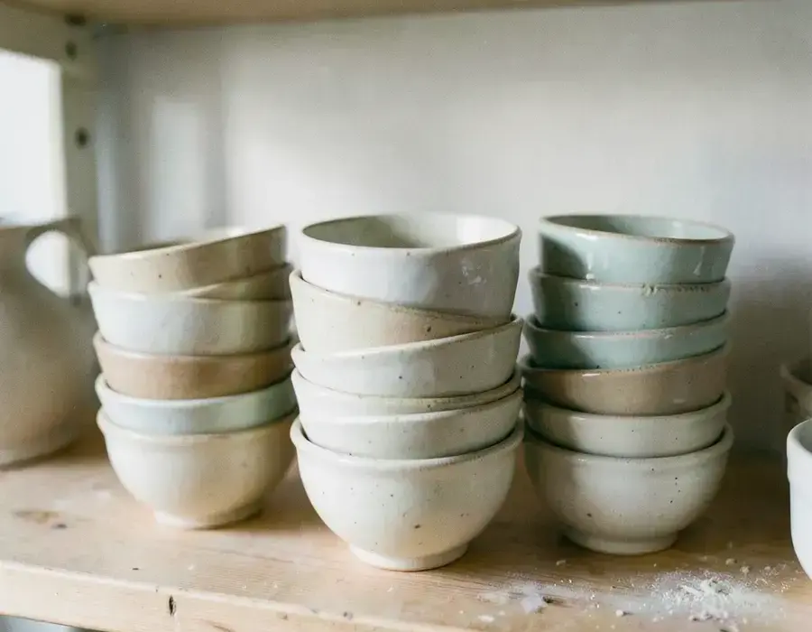 Small batch ceramic bowls stacked on a workshop shelf
